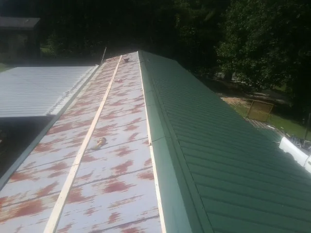 Old rusted panels beside newly installed green metal roofing — Wind Damage Roof Repair by Roofing Brothers in Clarksville