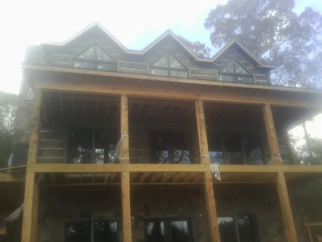 Dormers and porch framing on a large log home under construction — Roof Coating work by our crew in Clarksville